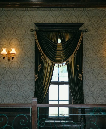 Gothic-style window with arched frames, candles, and dark drapes