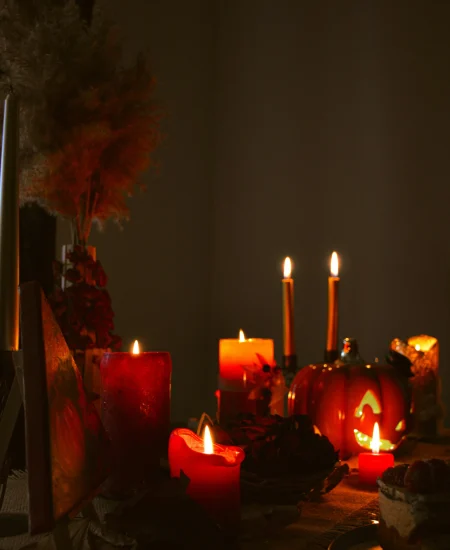 Halloween-themed candles arranged with pumpkins and dark spooky decor.