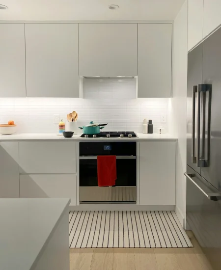 Minimalist kitchen with white cabinets, wood accents, and natural light