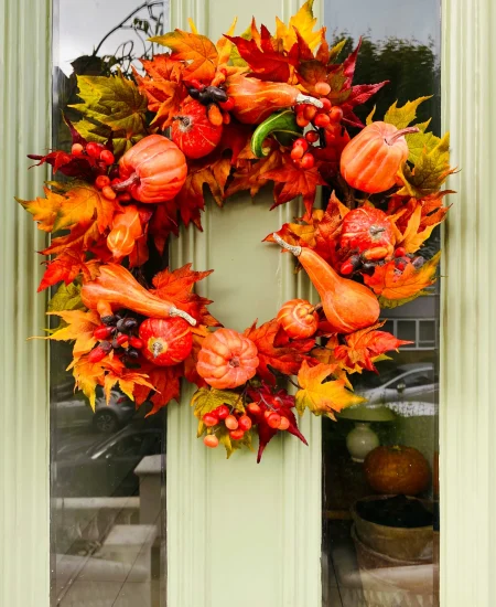 DIY Halloween door wreath made with mini pumpkins and autumn leaves.